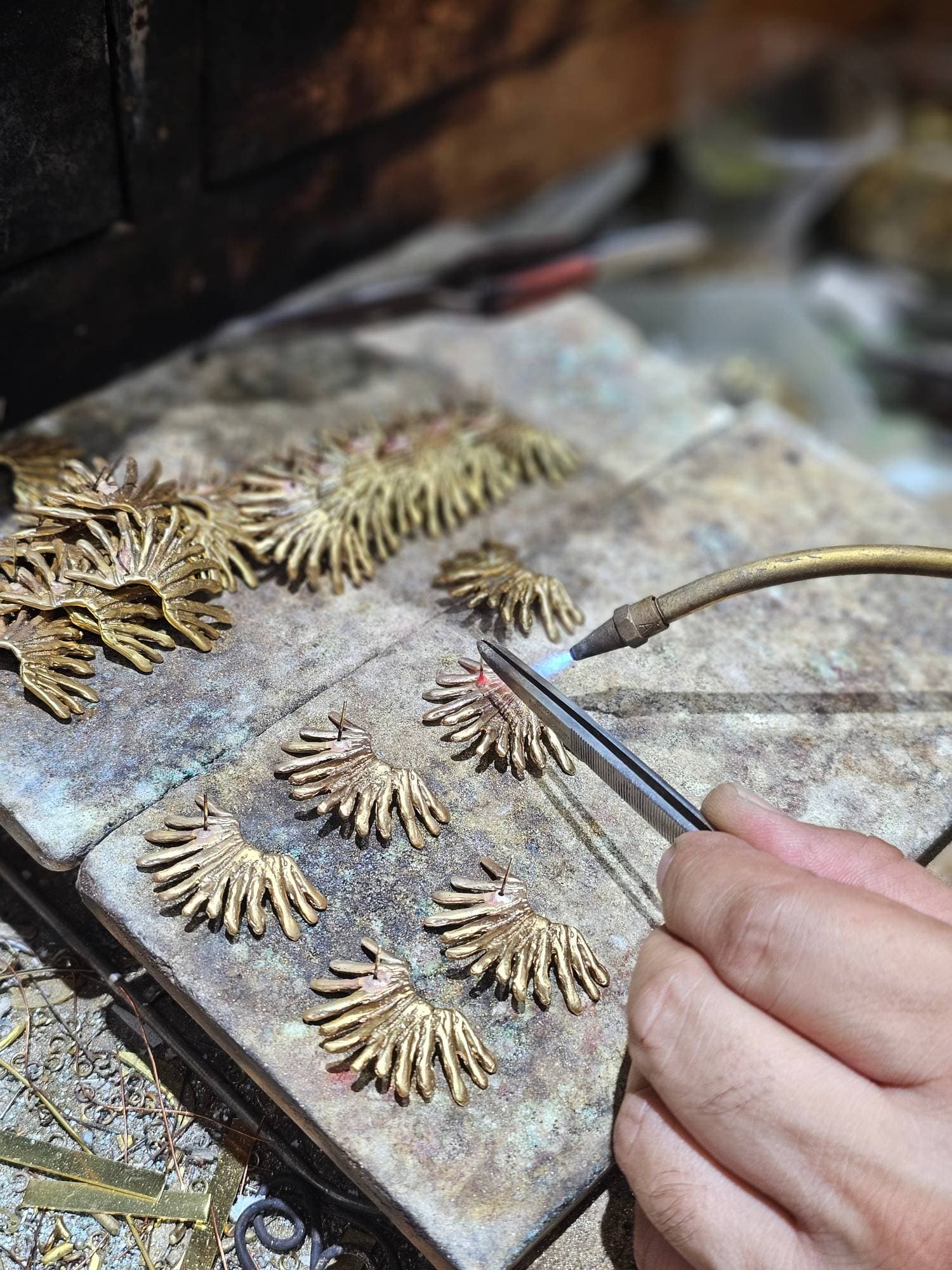 Earring posts being torch-soldered onto brass fan earrings