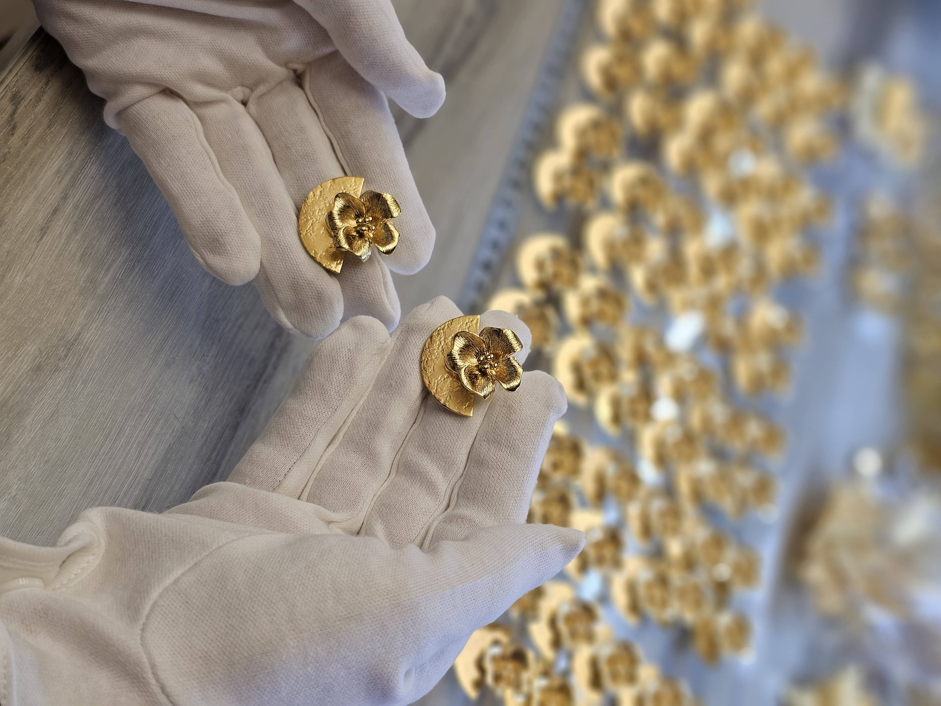 Gloved hands inspecting finished gold-plated earrings